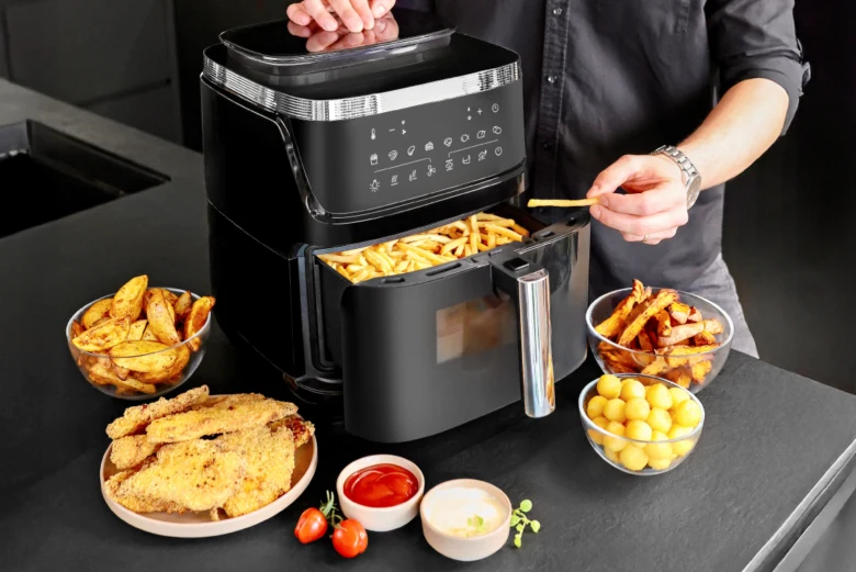 Člověk připravuje bramborové hranolky v horkovzdušné fritéze.