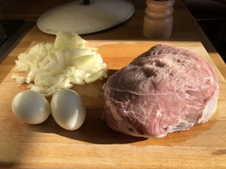 Surové hovězí maso s cibulí a vejci na dřevěném prknu.