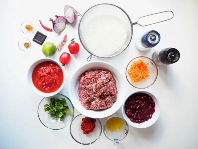 Suroviny pro přípravu chili con carne na bílém pozadí.