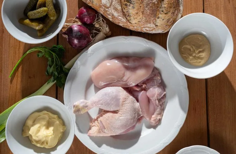 Surové kuřecí mas s ingrediencemi pro pomazánku na dřevěném povrchu.