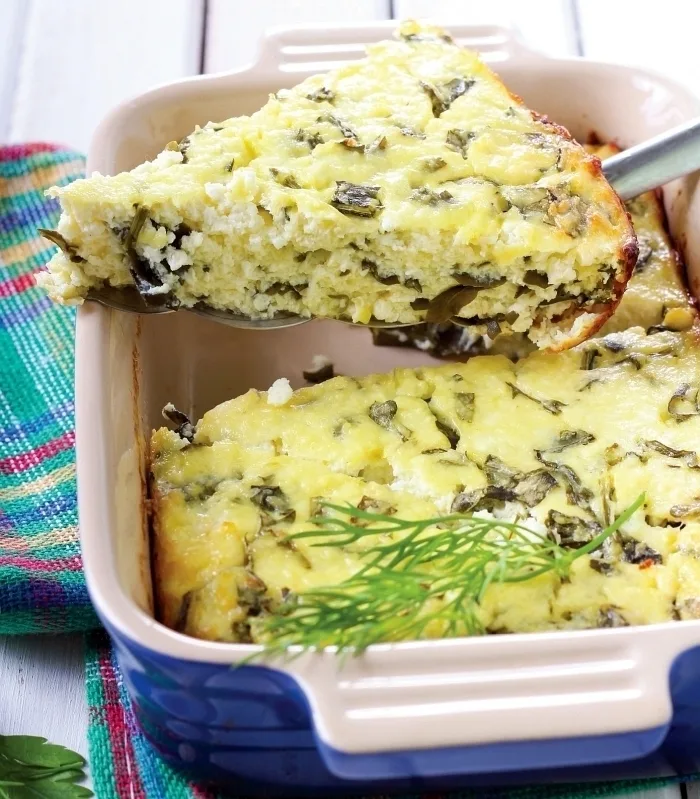 Kousek pečené rikota fritaty s bylinkami v keramické misce.