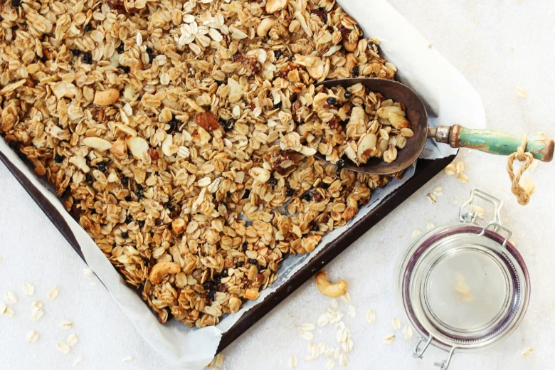 Domácí granola v pekáči s rozkrojenými ořechy a sušeným ovocem.
