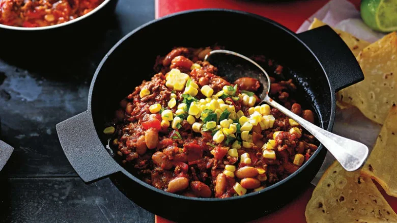 Chilli con carne s kukuřicí v hrnci na stolu.