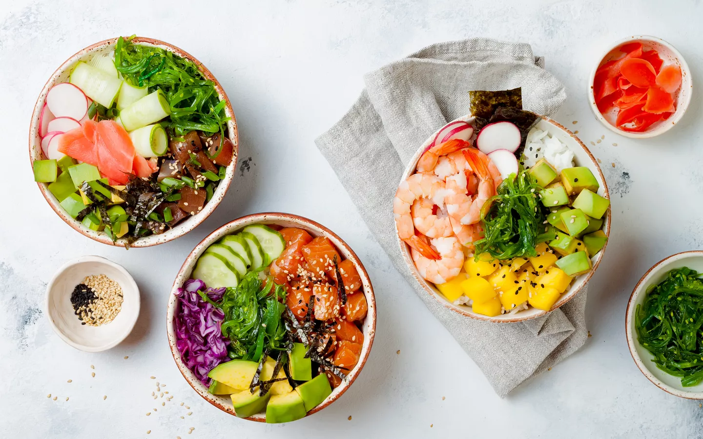 Tři barevné misky s pokem a sushi bowl plné čerstvých ingrediencí.