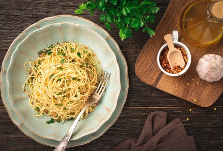 Pasta s česnekem, petrželkou a chilli vločkami na dřevěném stole.