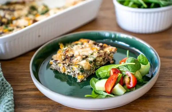 Kousek zeleninové lasagne s čerstvou salátovou přílohou.