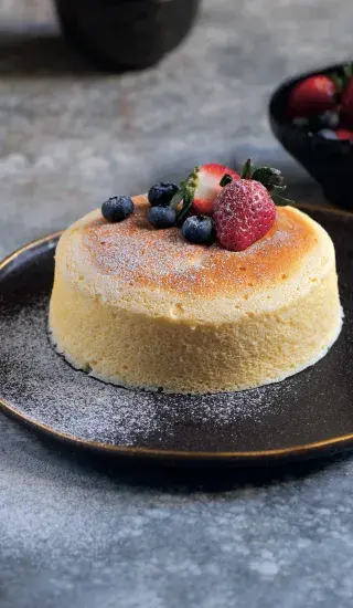 Japonský cheesecake s jahodami a borůvkami na talíři.