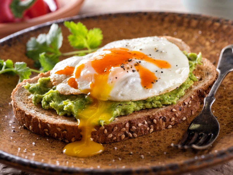 Krájený chlév s guacamole a smaženým vejcem na talíři.