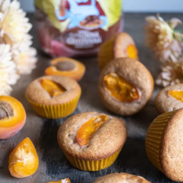 Zlatohnědé muffiny s plnkou z meruněk na tmavém povrchu.