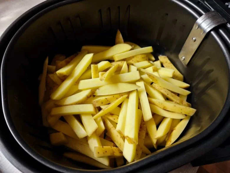 Surové hranolky v košíku horkovzdušné fritézy.