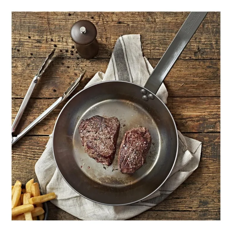 Dva sezónované steak v pánvi se zlatými bramborovými hranolky.