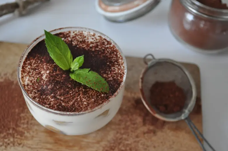 Hotový dezert Tiramisu v skleněné misce s čokoládou a máty.