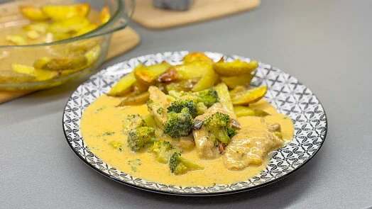 Pekčené brambory s brokolicí v krémové omáčce na talíři.