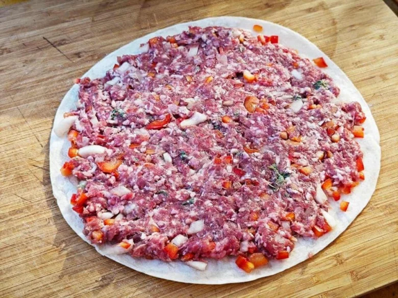 Tortilla s mletým masem připravená k pečení na dřevěném prknu.