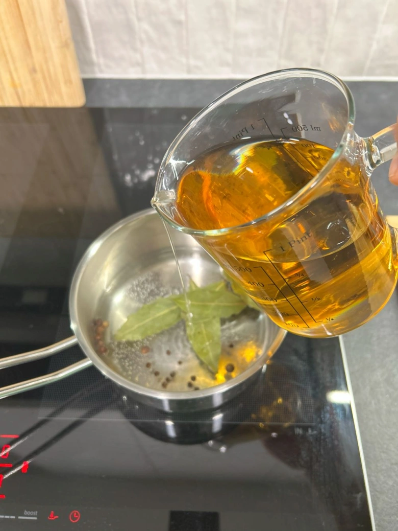 Nalévání vývaru do hrnce s kořením pro utopence