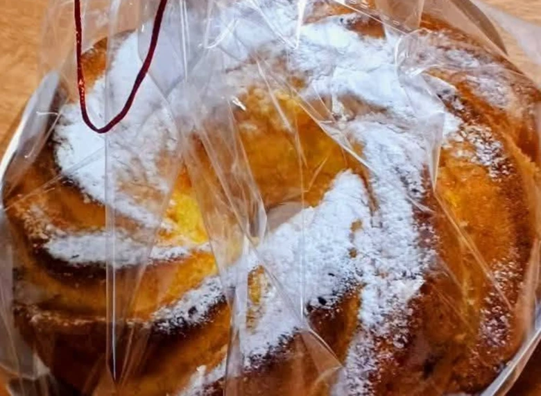 Zlatohnědá bábovka v krabičce posypaná moučkou na cukr.