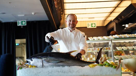 Šéfkuchař krájí čerstvou tuňáka na ledě v restauraci.