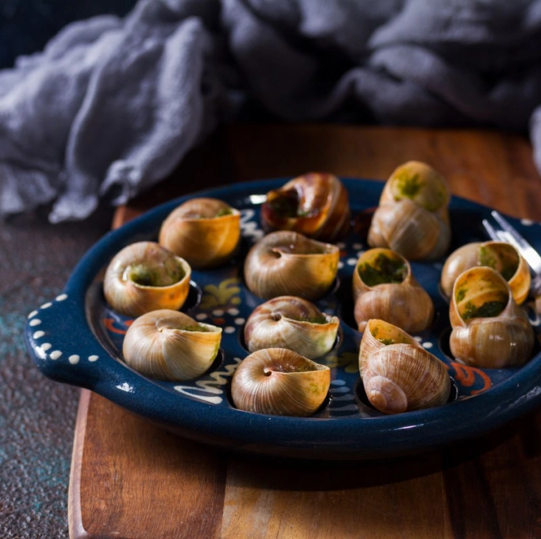 Pekně připravené escargoty na modrém talíři.