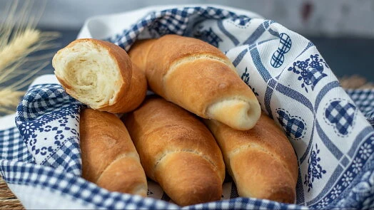 Domácí rohlíky v košíku s modro-červeným ubrusem.