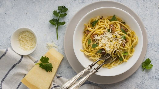 Mísa se špagetami aglio olio s parmezánem, petrželkou a kouskem parmazánu.
