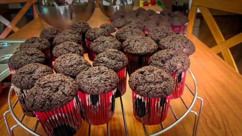 Čokoládové muffiny v červených papírových formách na mřížce.