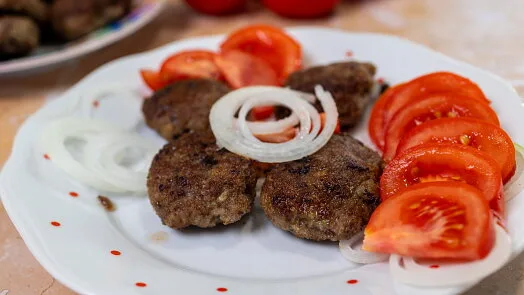 Grilled meat patties with tomato and onion