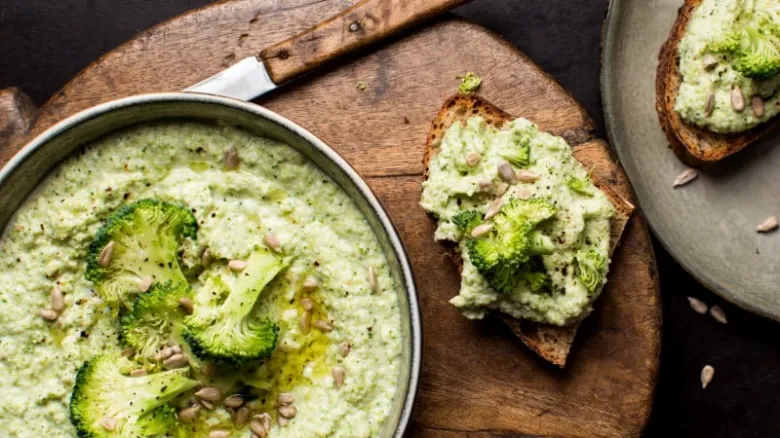 Krušková polévka z brokolice s toastsy na dřevěném talíři.