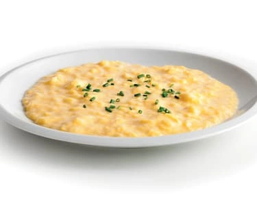 Hot krupicová kaše s nasekanou zeleninou na bílém talíři.