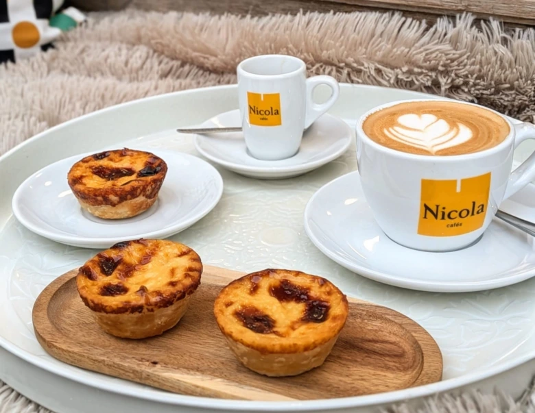Portugalské dezerty pastel de nata s kávou na podnose.