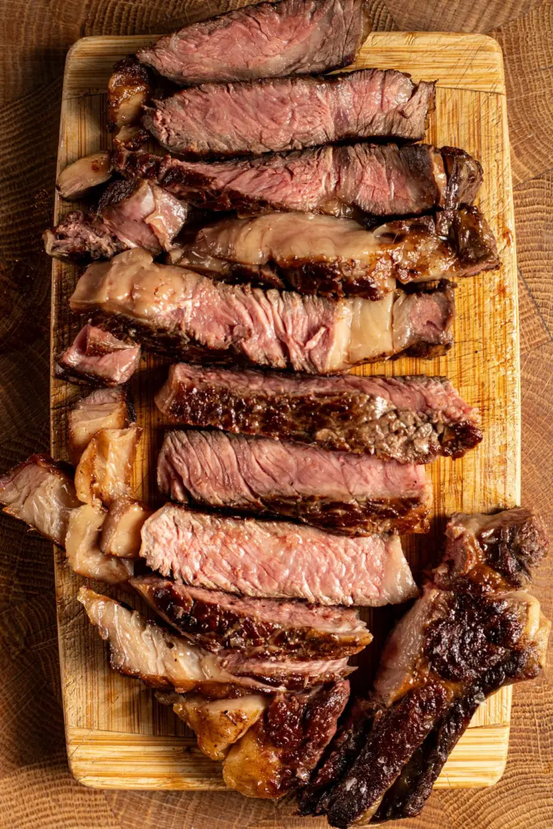 Nakrájený steak na dřevěném prkénku s viditelnou vnitřní texturou.