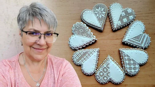 Žena s ozdobenými srdcovými perníčky na dřevěném povrchu.