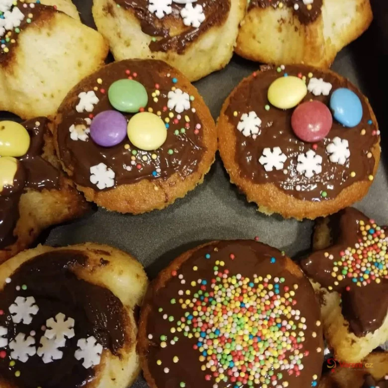 Čokoládové muffiny s barevnými cukrovkami na plechu.