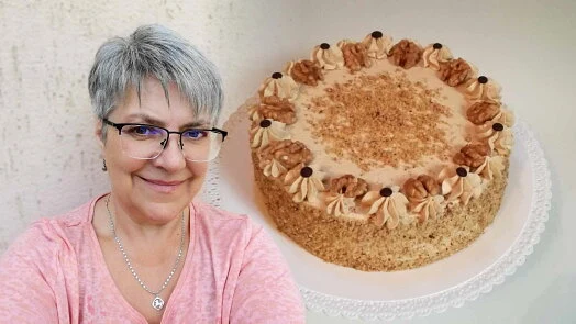 Žena stojí vedle dortu s ořechy na bílém talíři.