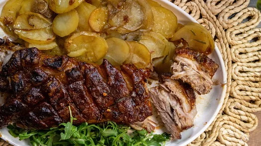 Pekoucí bůček s bramborami na talíři