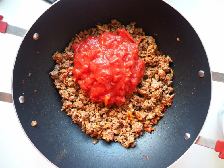 Mleté maso s rajčatovou omáčkou v pánvi pro chilli con carne.