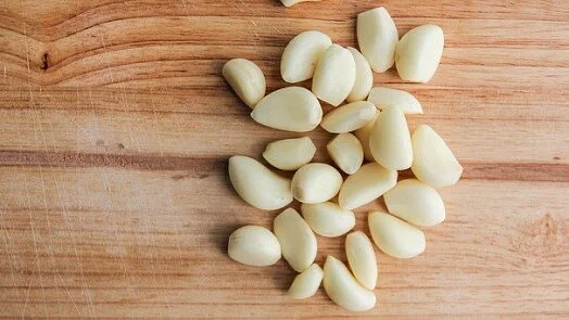 Loupky česneku na dřevěném prknu pro recept