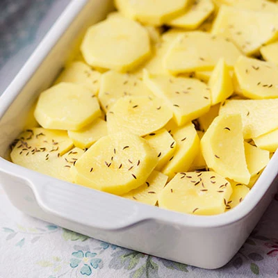 Nakrájené brambory s bylinkami v pekáči před péčením