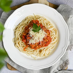 Pasta s masovou omáčkou na bílém talíři.