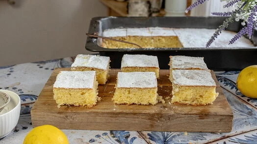 Kusky citronové bábetu posypané cukrem na dřevěném prkénku.