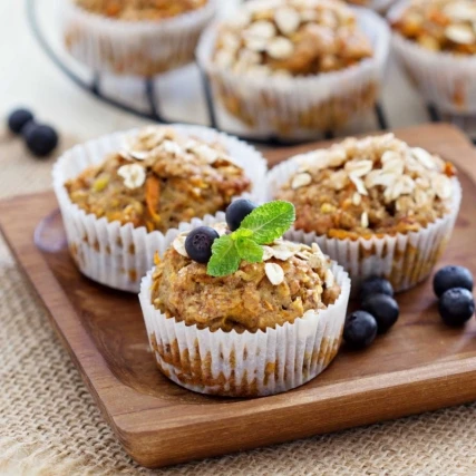 Zdravé ovesné muffiny s borůvkami a mátou na dřevěném podnose.