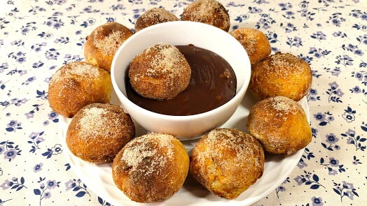 Zlaté churro s cukrem obklopují misku čokoládové omáčky.
