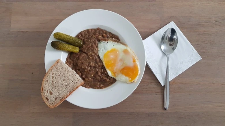 Pohled na talíř s pečenými fazolemi, vejcem a chlebem.