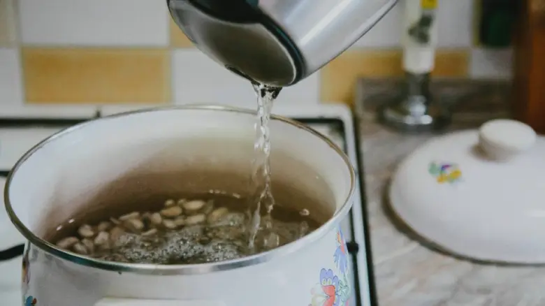 Voda se nalévá do hrnce s fazolemi na vaření polévky.