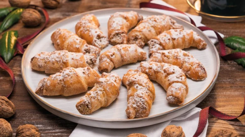 Zlaté lístkové sušenky s ořechovou náplní posypané cukrem.