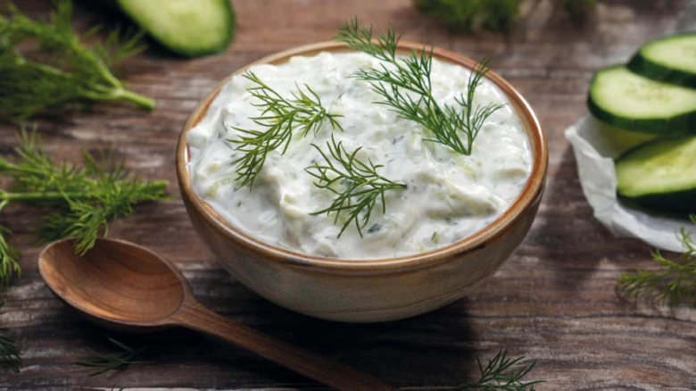 Okurkový salát s bylinkami v dřevěné misce na stolu.