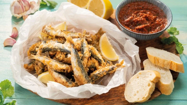 Smařené sardinové placky podávané s citronem, chlebem a omátkou.
