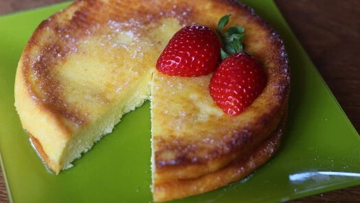 Japonský cheesecake s jahodami na zeleném talíři.