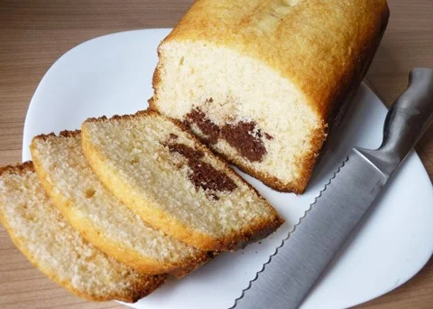 Nakrájená bábovka s čokoládovým středem na bílém talíři.