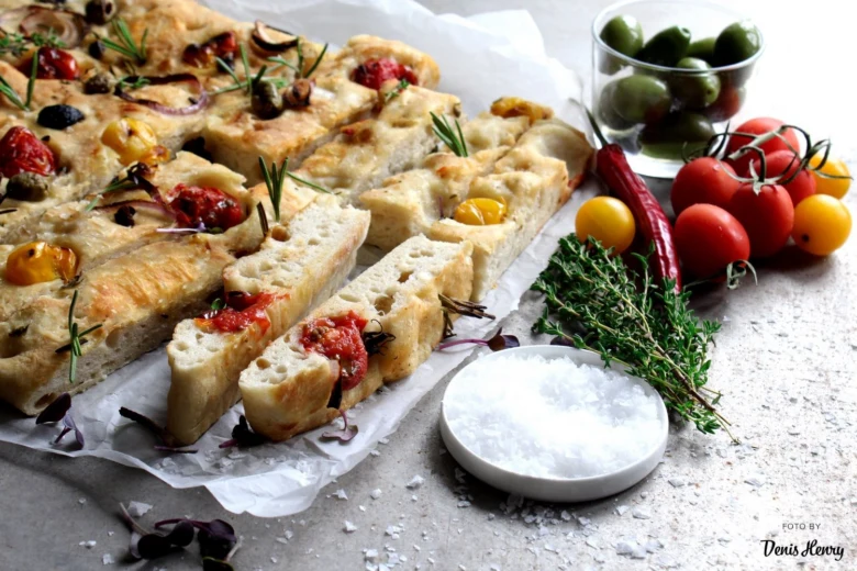 Italská focaccia s rajčaty a olivami na italském stole.