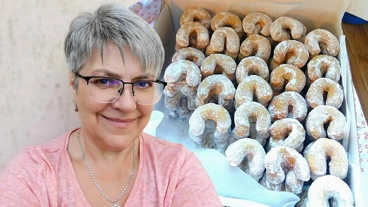 Žena s krabicí vanilkových rohlíčků posypaných cukrem.